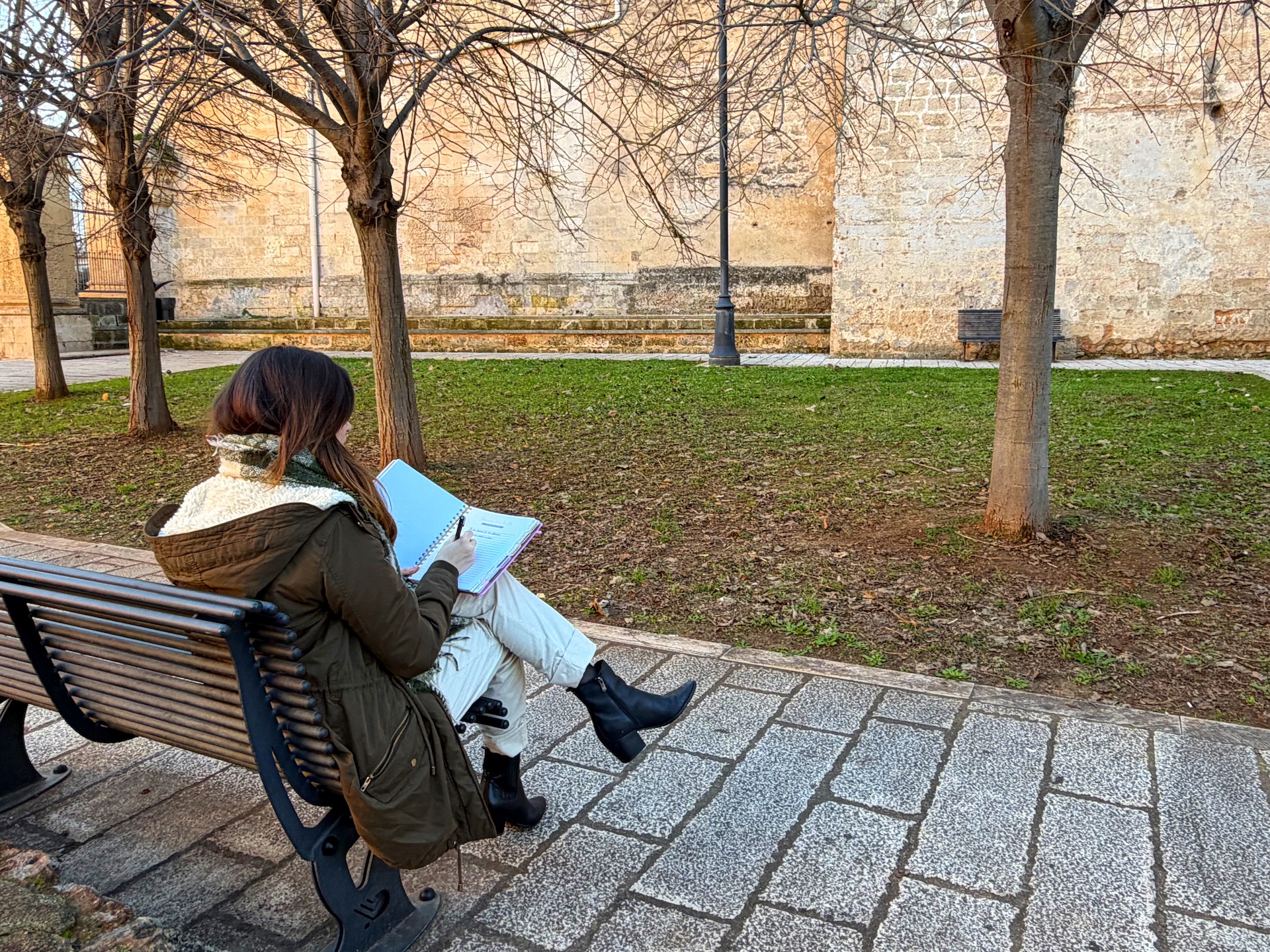 Ragazza seduta sulla panchina di un parco che scrive sull'agenda
