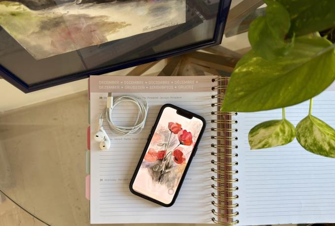 Smartphone con sfondo che riproduce un quadro ad acquerello, agenda e cuffie per cellulare