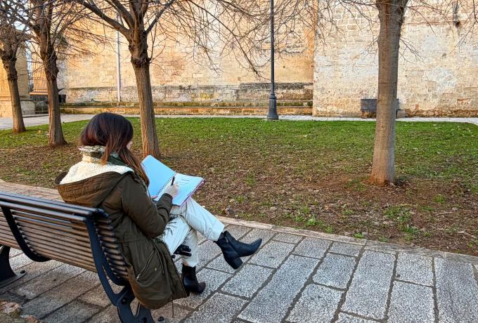 Ragazza seduta sulla panchina di un parco che scrive sull'agenda
